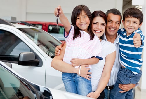 Family holding keys to their new car at the dealer